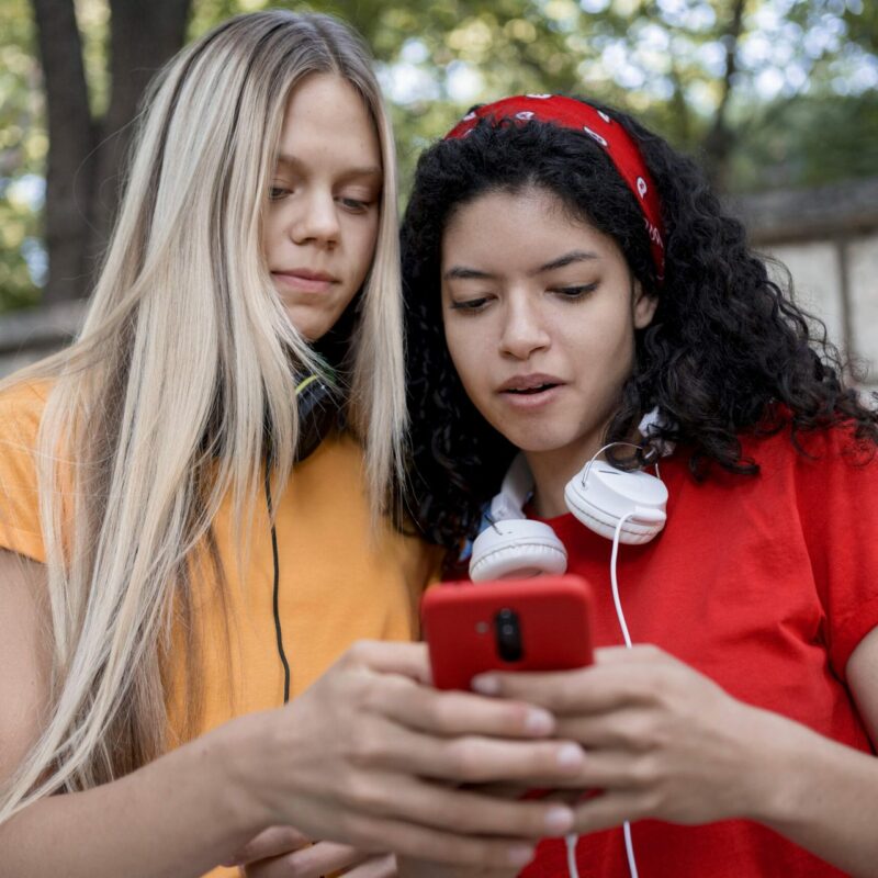Chicas jóvenes mirando el teléfono juntas