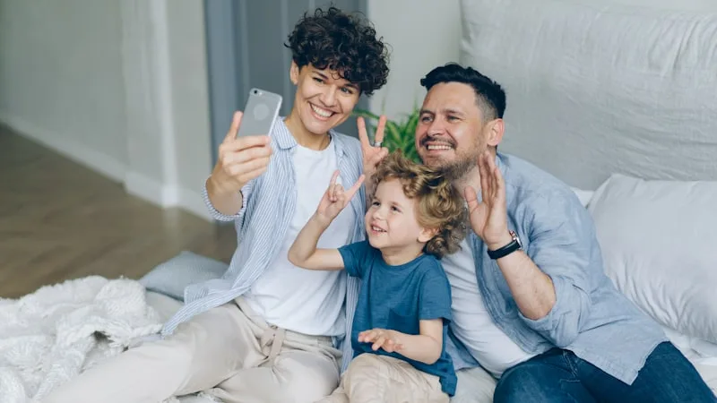 Familia feliz usando un móvil sin redes sociales en casa